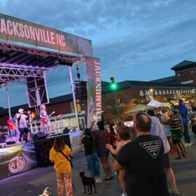 Band of outside stage with people listening.