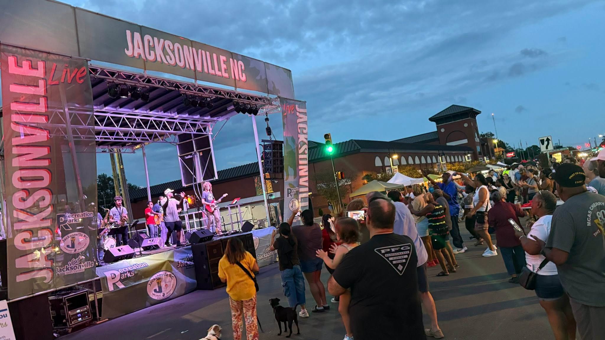 Band of outside stage with people listening.
